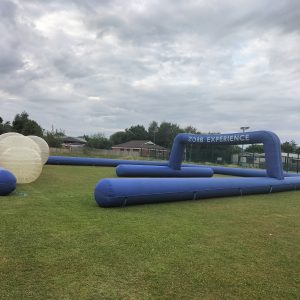 Inflatable Zorb experience setup featuring a large blue inflatable frame and transparent Zorb balls.