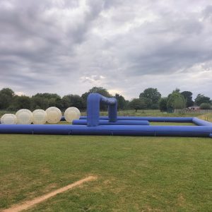 Large inflatable Zorb ball course with multiple transparent Zorb balls on a grassy field.