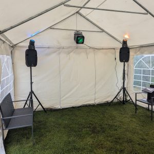 An indoor gazebo featuring two speakers, colored lights, and seating arrangements.