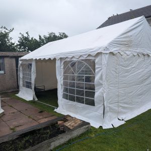 White outdoor gazebo with transparent windows set up in a grassy area.