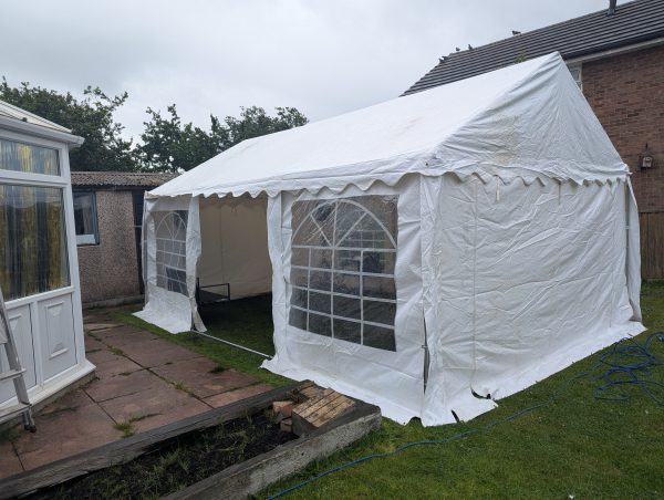 White outdoor gazebo with transparent windows set up in a grassy area.